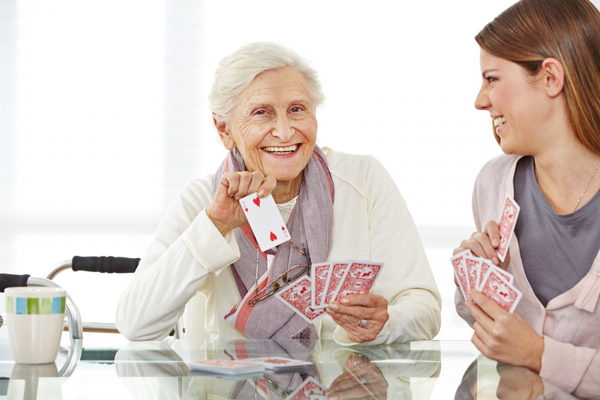 Frau spielt mit Seniorin im Seniorenheim Karten