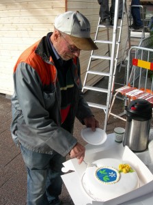 Kjell Johansson tog ett par minuters paus i byggandet för att skåra tårtan. (Foto: Håkan Johansson)